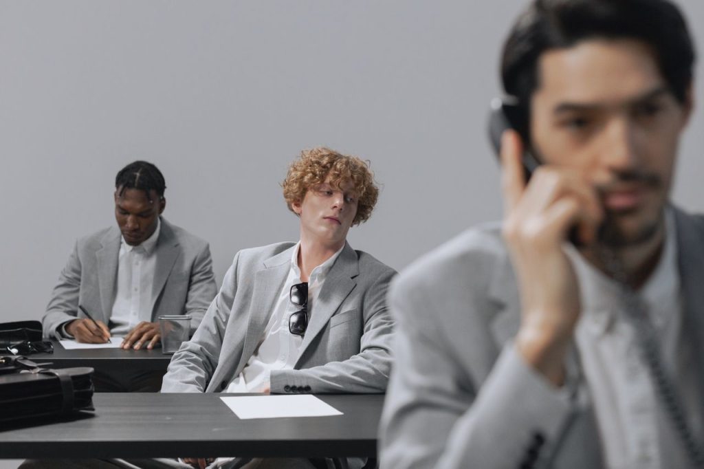 The Art of Drawing Readers In: Your attractive post title goes here Three office workers in grey suits focusing on tasks in a professional setting.